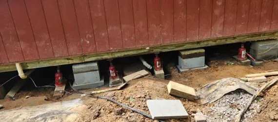House leveling process using hydraulic jacks to lift foundation for repair