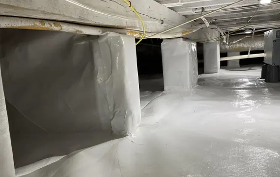Crawlspace with complete white vapor barrier and sealed foundation piers preventing moisture